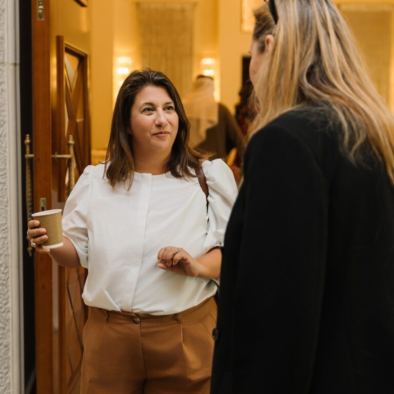 Two female attendees engaged in conversation at The Syndicate Global Dubai event at the One&Only hotel.